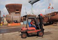 011_73_5187 Ein Gabelstapler wird ber das Betriebsgelnde der Hamburger Sietas-Werft gefahren. Im Hintergrund das Bugelement und weitere Stahlsegmente eines Schiffsneubaus. 