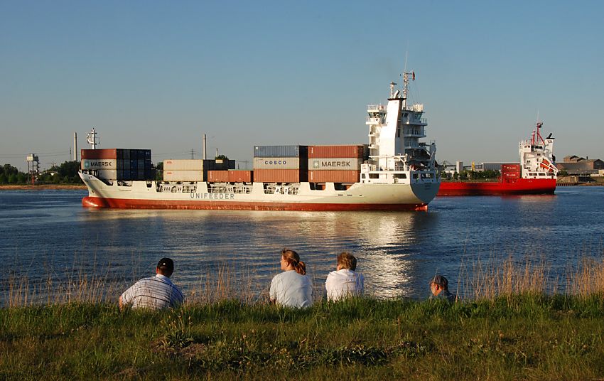 011_15592 zwei Containerschiffe / Containerfeeder liegen auf dem Khlbrand ( Sderelbe ) und warten auf einen Liegeplatz am Terminal Altenwerder. Hamburg Touristen sitzen in der Abendsonne auf dem Elbdeich und beobachten den Schiffsverkehr. www.fotograf-hamburg.de