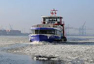 011_26073 Winter in Hamburg- eine Hafenfhre kommt von Hamburg Finkenwerder und fhrt durch den Eisgang auf der Elbe Richtung St. Pauli Landungsbrcken. Im Hintergrund sind die Containerbrcken vom Containerterminal Predhlkai zu erkennnen. www.hamburg-fotograf.com