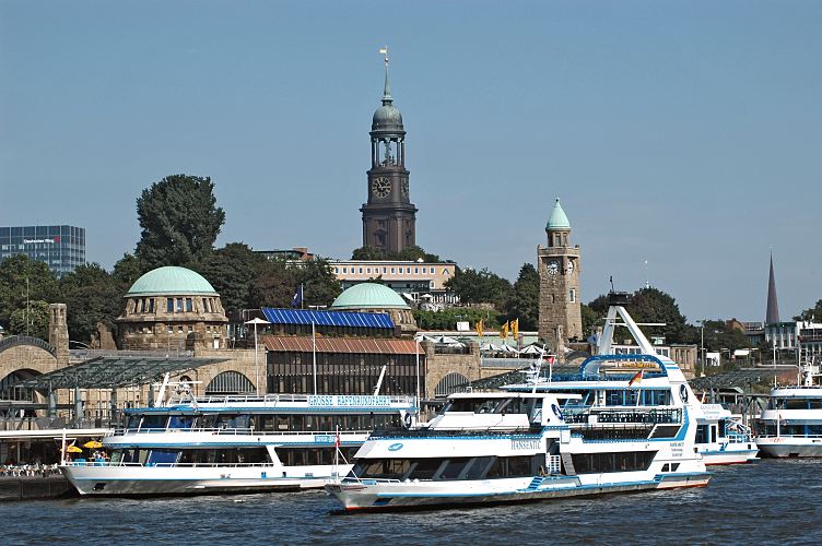 Fotografie der St. Pauli Landungsbrcken, Schiffe der Hafenrundfahrt und der St. Michaeliskirche.  011_26077 Schiffe der Hafenrundfahrt Hamburgs liegen an den St. Pauli Landungsbrcken - die Hafenrundfahrt ist eine beliebte Touristenattraktion. Das Abfertigungsgebude mit den beiden Kupfergedeckten Kuppeln und dem Tiede- und Uhrenturm wurde von 1907 - 1909 aus Tuffstein errichtet. Die Landungsbrcken haben eine Lnge von ca. 205 m; die Anlage wurde 2003 unter Denkmalschutz gestellt. Hinter dem Gebude der Jugendherberge am Stintfang ragt das Hamburger Wahrzeichen, der Turm der Michaeliskirceh empor. Auf der Plattform unter der Kuppel geniessen die Hamburger Touristen den Ausblick ber die Hansestadt, die Elbe und den Hafen.www.hamburg-fotograf.com