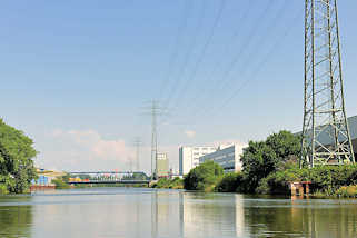 5867 Hochspannungsleitungen, Hochspannungsmasten entlang des Tidekanals in Hamburg Billbrook; im Hintergrund die Brcke der Moorfleeter Strasse.