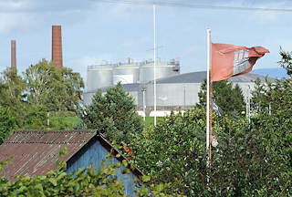 8003 Hamburg Flagge im Kleingartengelnde - ltanks und Schornsteine einer Erdl-Raffinerie im Harburger Seehafen.