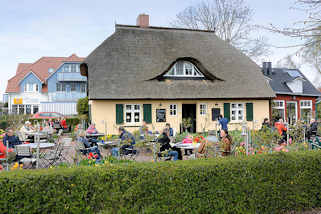 155_0536 Gartenlokal, Gste sitzen im Blumengarten an Tischen in der Sonne - Reetdachhaus mit Dachfenster